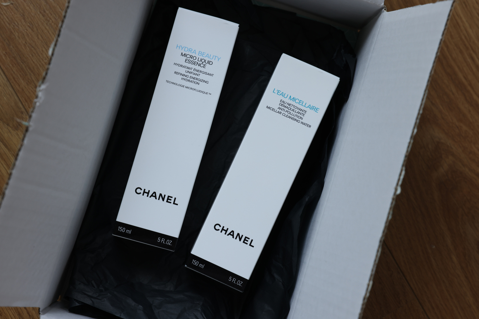 NETHERLANDS, LEIDEN - JULY 12, 2022: Chanel Micellar Water and Micro Liquid Essence in Box on Wooden Table, Top View